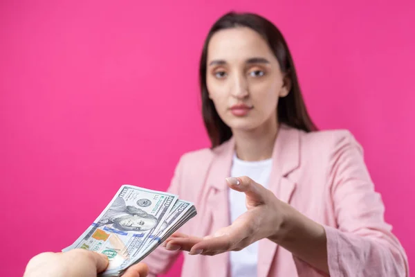 분홍색 자켓을 여자는 배경에 달러로 뇌물을 받는다 — 스톡 사진