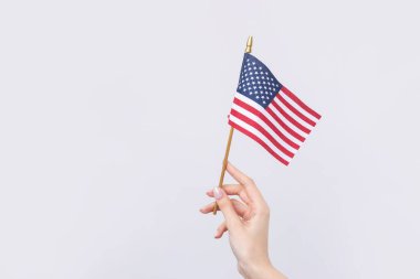 Güzel bir kadın eli beyaz bir arka planda Amerikan bayrağı taşıyor..