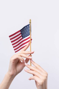 Güzel bir kadın eli beyaz bir arka planda Amerikan bayrağı taşıyor..