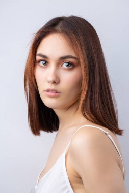 Temiz ciltli, doğal makyajlı ve gri arka planda beyaz dişli güzel bir kadın.