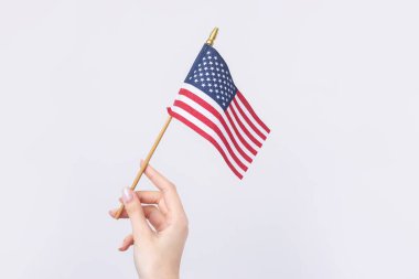 Güzel bir kadın eli beyaz bir arka planda Amerikan bayrağı taşıyor..