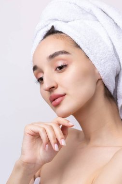 Kalın kaşlı güzel bir kız, beyaz arka planda mükemmel bir ten, kafasında havlu, güzel bir fotoğraf..