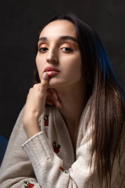 Stüdyoda uzun saçlı genç bir esmerin portresi. Koyu renkli dramatik fotoğraf.