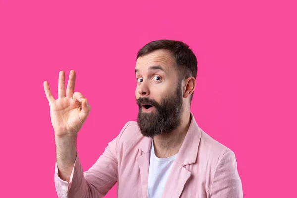 一个穿着粉色夹克笑着的年轻人的画像 男人站在独立的红色背景下 摆出一副不错的姿势 — 图库照片
