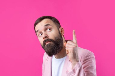 Pembe ceketli sakallı yakışıklı adam, izole edilmiş kırmızı bir arka plan düşünüyor..