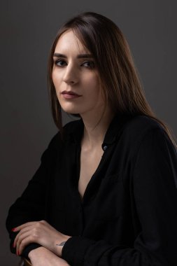 Stüdyoda uzun saçlı genç bir esmerin portresi. Koyu renkli dramatik fotoğraf.