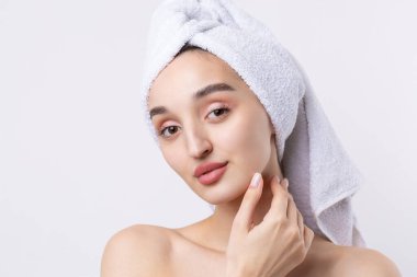 Kalın kaşlı güzel bir kız, beyaz arka planda mükemmel bir ten, kafasında havlu, güzel bir fotoğraf..