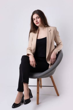 Stüdyoda uzun saçlı genç bir esmerin portresi. Beyaz arka planda sandalyede oturan tatlı kız..