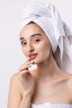Kalın kaşlı güzel bir kız, beyaz arka planda mükemmel bir ten, kafasında havlu, güzel bir fotoğraf..