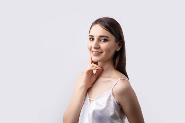 Temiz ciltli, doğal makyajlı ve gri arka planda beyaz dişli güzel bir kadın.