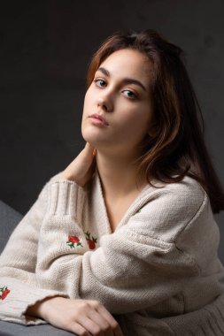 Stüdyoda uzun saçlı genç bir esmerin portresi. Koyu renkli dramatik fotoğraf.
