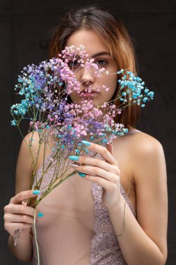 Zarif, çıplak bir beden giymiş güzel seksi bir bayan elinde çiçekler tutuyor. Moda mankeni kızın güzel portresi stüdyoda..