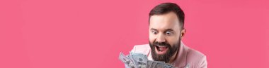 Pembe ceketli sakallı, mutlu genç bir iş adamının portresi kırmızı bir stüdyonun arka planında bize dolar banknotları gösteriyor. Tat, para kokusu..