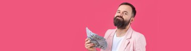 Pembe ceketli sakallı, mutlu genç bir iş adamının portresi kırmızı bir stüdyonun arka planında bize dolar banknotları gösteriyor. Tat, para kokusu..