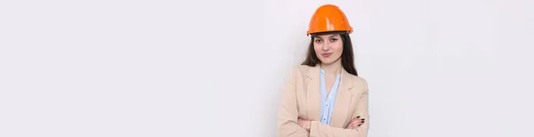 白い背景にはスーツ姿の少女建築家とオレンジの建設用ヘルメットが立っている — ストック写真