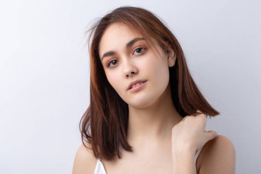 Temiz ciltli, doğal makyajlı ve gri arka planda beyaz dişli güzel bir kadın.