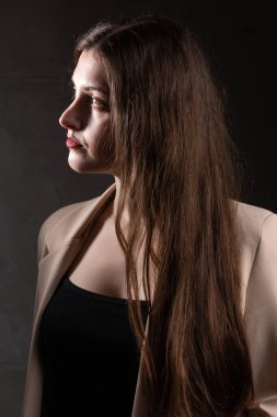 Stüdyoda uzun saçlı genç bir esmerin portresi. Koyu renkli dramatik fotoğraf.