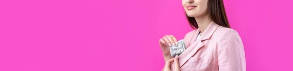 ピンクのジャケットの女性はドル紙幣を持っている困惑したビジネスの女の子は赤い背景に立ってドルを隠します — ストック写真