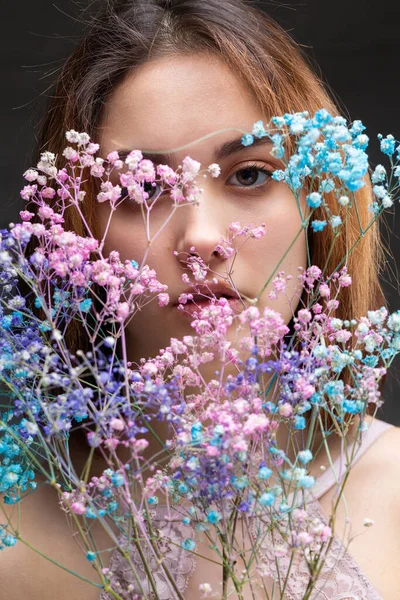 Zarif, çıplak bir beden giymiş güzel seksi bir bayan elinde çiçekler tutuyor. Moda mankeni kızın güzel portresi stüdyoda..