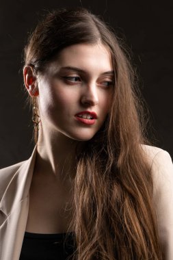 Stüdyoda uzun saçlı genç bir esmerin portresi. Koyu renkli dramatik fotoğraf.