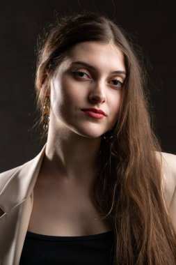 Stüdyoda uzun saçlı genç bir esmerin portresi. Koyu renkli dramatik fotoğraf.