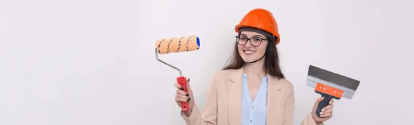 戴着橙色建筑头盔的女工程师 手上拿着白色背景的粉刷工具 — 图库照片