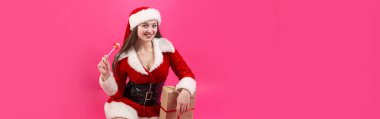 Kırmızı arka planda Noel Baba kostümü giymiş güzel bir kadın..