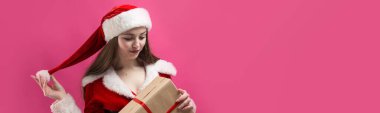 Kırmızı arka planda Noel Baba kostümü giymiş güzel bir kadın..