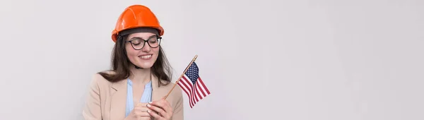 一个戴着建筑用头盔和美国国旗的女孩站在白色的背景上 很高兴 — 图库照片