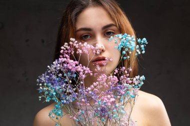 Zarif, çıplak bir beden giymiş güzel seksi bir bayan elinde çiçekler tutuyor. Moda mankeni kızın güzel portresi stüdyoda..