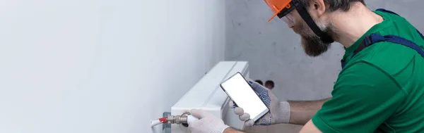 Een Mannelijke Loodgieter Installeert Een Radiator Het Verwarmingssysteem Van Een — Stockfoto