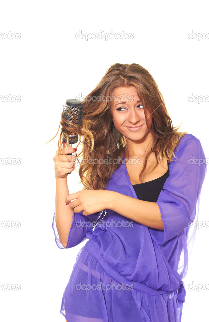 Attractive girl in a lilac blouse combing her hair round comb.