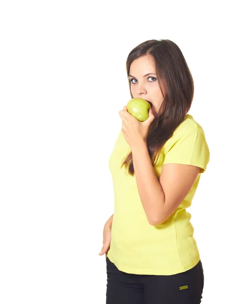 Menina atraente na camisa amarela está comendo uma maçã verde . — Fotografia de Stock