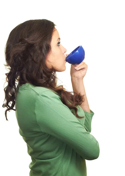 Chica atractiva en una camisa verde bebiendo de una taza azul . — Foto de Stock