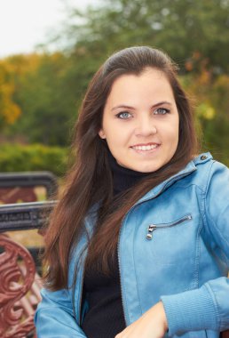 bir bankta oturan mavi ceket çekici gülümseyen kız