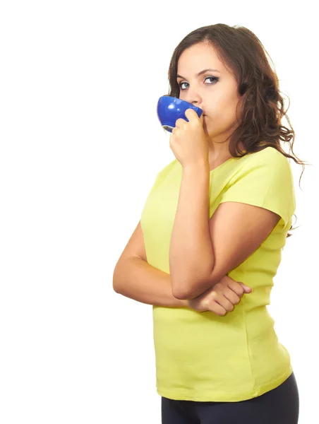 Attractive girl in yellow shirt drinking from blue cup. — Stock Photo, Image