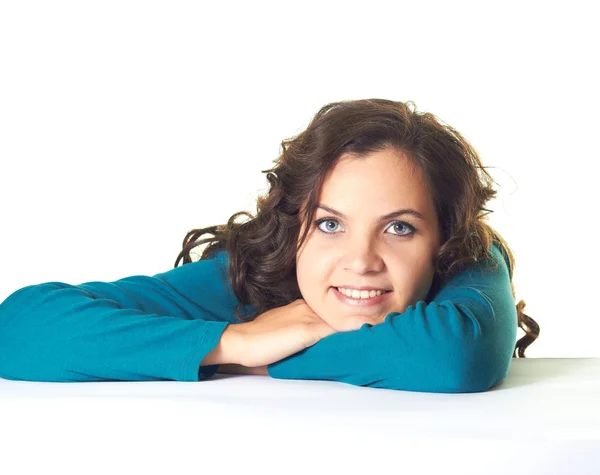 Atrakcyjny dziewczynka uśmiechający się w niebieską koszulę siedzi przy stole. — Zdjęcie stockowe
