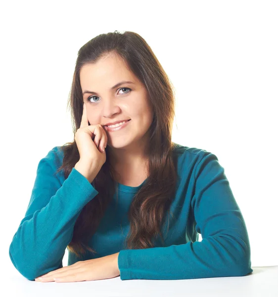 Привлекательная молодая улыбающаяся девушка в голубой рубашке сидит за столом — стоковое фото