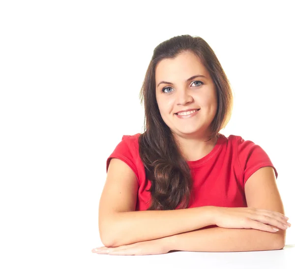 Aantrekkelijke jonge lachende meisje in een rode shirt zittend op de tabl — Stockfoto