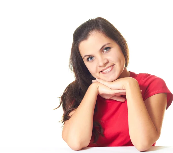 Aantrekkelijke jonge lachende meisje in een rode shirt zittend op de tabl — Stockfoto