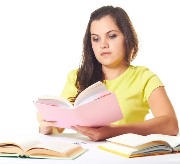 Attractive young girl in yellow shirt sitting at the table and r — Stock Photo, Image