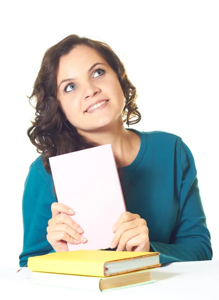 Attractive young smiling girl in a blue shirt sitting at a table — Stock Photo, Image