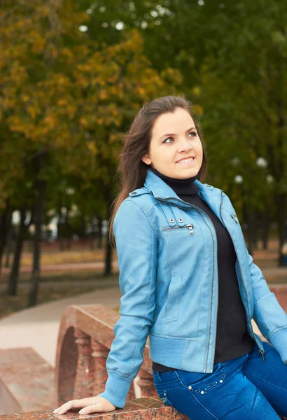 Muchacha joven atractiva en una chaqueta azul y pantalones vaqueros azules a la par Fotos De Stock Sin Royalties Gratis