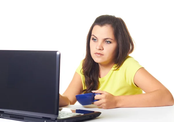 Attraktiv ung kvinna i en gul skjorta som arbetar på laptop och h — Stockfoto