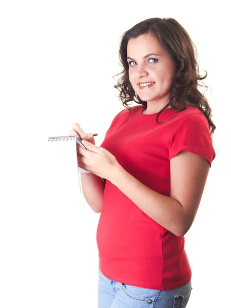 Attractive smiling girl in a red shirt writing something in a no — Stock Photo, Image