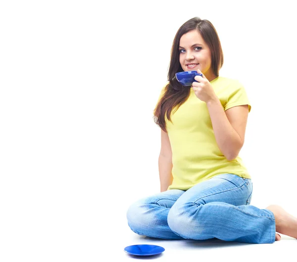 Attractive young woman in a yellow shirt and blue jeans sitting — Stock Photo, Image