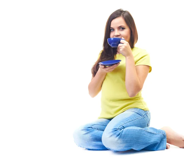 Attractive young woman in a yellow shirt and blue jeans sitting — Stock Photo, Image