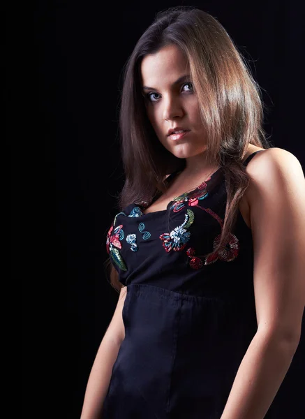 Aantrekkelijke jonge vrouw in een zwarte blouse op een zwarte achtergrond — Stockfoto