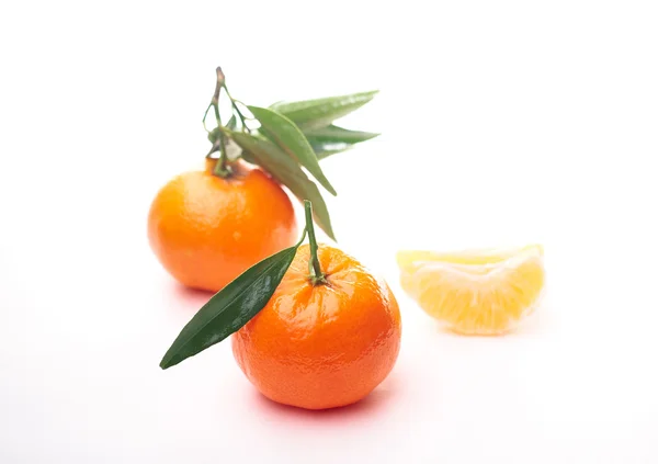 Two juicy tangerines with green leaves and small tangerines sl — Stock Photo, Image