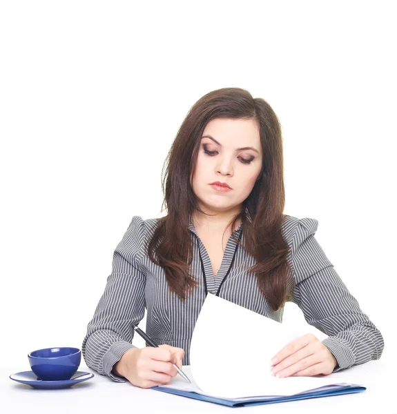 Attraktive junge Frau in grauer Bluse am Tisch sitzend und — Stockfoto